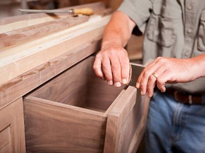 Carpenter/cabinet maker smoothing out a drawer top with a scraper.